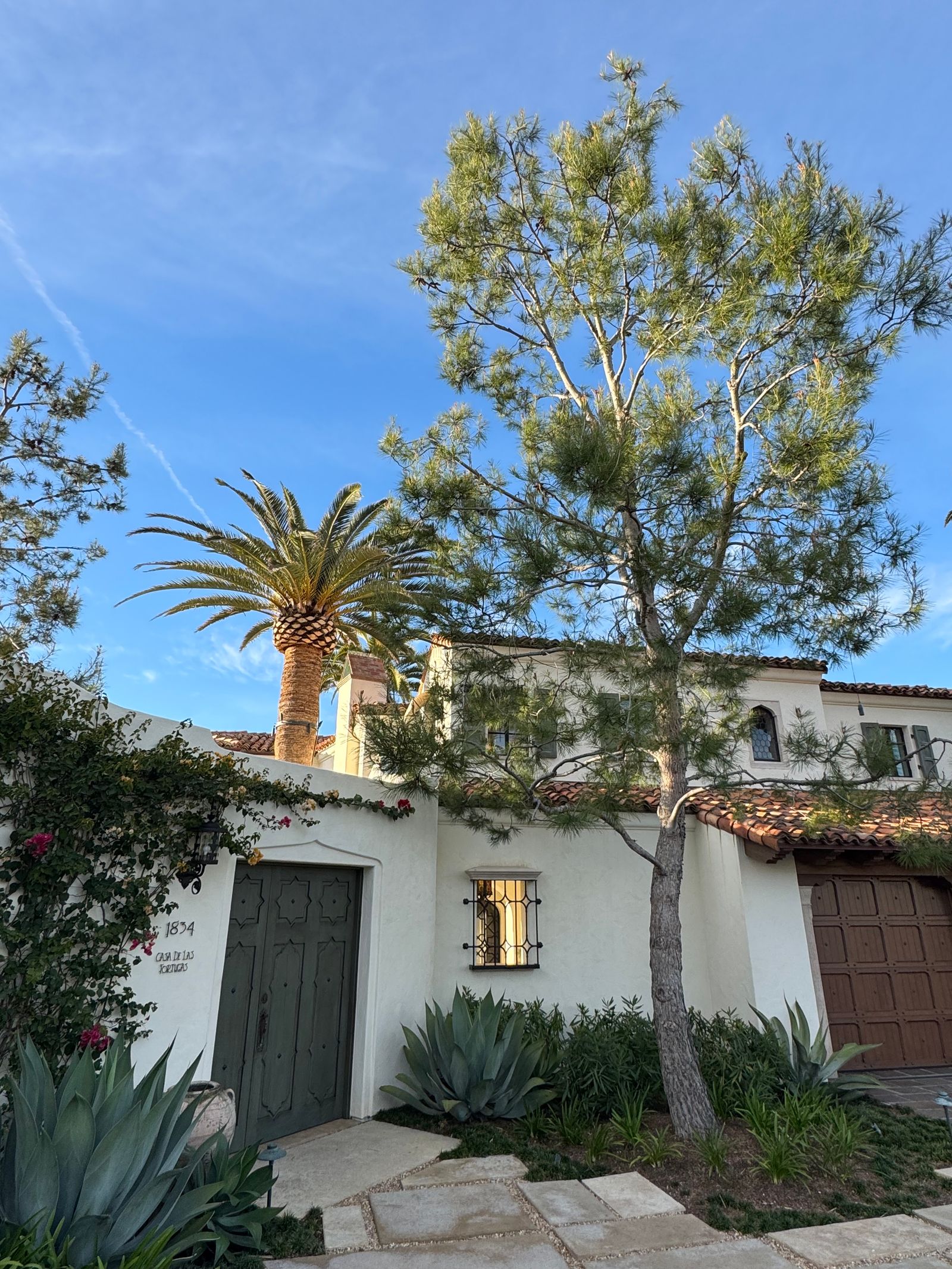 Real Spanish Revival home exterior in San Diego with a tile roof and mature landscaping